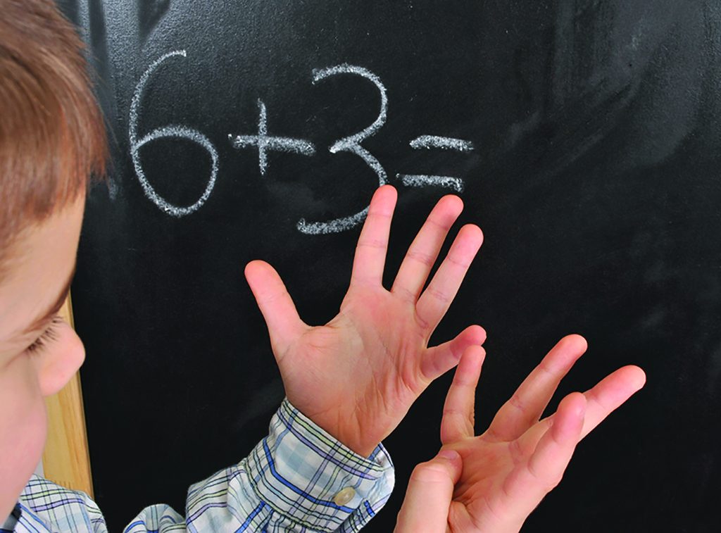 Junior pupil by the blackboard is solving mathematical problems