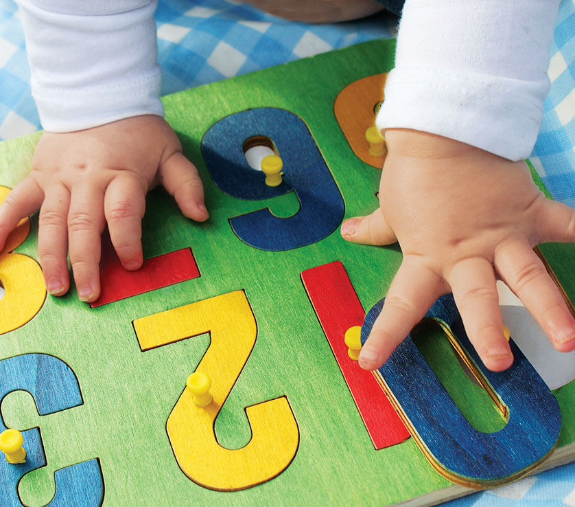 a baby's hands playing with a number puzzle