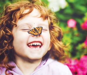 laughing child with butterfly on their nose